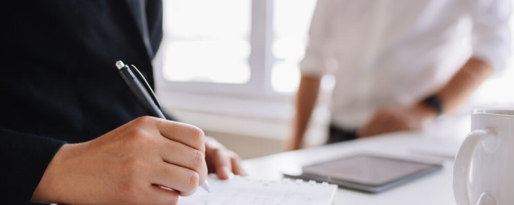 Man's hand, writing on a sheet of paper