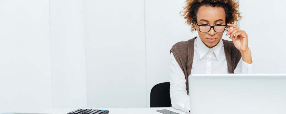 Woman with glasses, working on a laptop