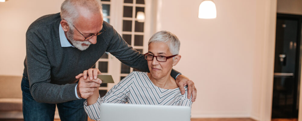 Adult couple with a credit card, woman looking at a laptop screen